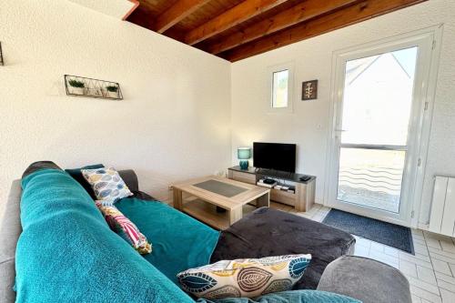 un salon avec un canapé bleu et une table dans l'établissement Charmante maisonnette Terrasse - Proche plages, à Guidel