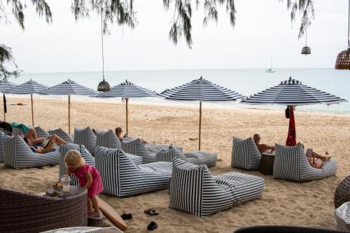a group of people on a beach with umbrellas at Long Beach Chalet - SHA Extra Plus in Ko Lanta