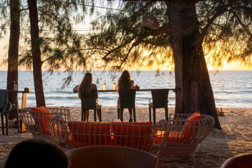 a group of people sitting at a table on the beach at Long Beach Chalet - SHA Extra Plus in Ko Lanta
