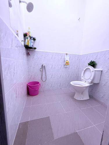 a bathroom with a toilet and a pink bucket at De Bunga Homestay in Parit Raja