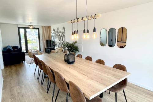 une salle à manger avec une grande table et des chaises en bois dans l'établissement Duplex neuf Hyper Design - Piscine chauffée, à Riantec