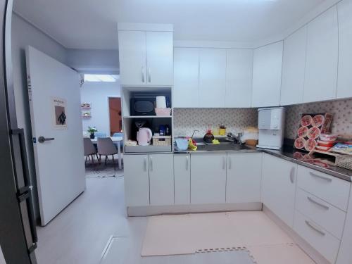 a kitchen with white cabinets and a dining room at Daejeon Station Seongsimdang Remodeled Detached House 'Ini' House in Daejeon