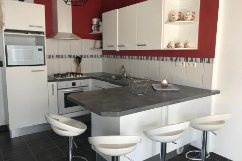 une cuisine avec des armoires blanches et un comptoir avec des tabourets dans l'établissement Maisonnette de pêcheur À 200m de la plage, à Ploemeur