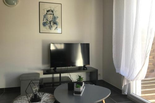 un salon avec une télévision et une table dans l'établissement Maisonnette de pêcheur À 200m de la plage, à Ploemeur