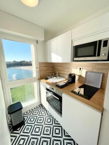 une cuisine avec un comptoir, un évier et une fenêtre dans l'établissement Pieds Dans L'Eau T2 Archi Cosy - Vue mer 180, à Ploemeur