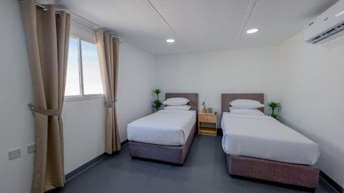 two beds in a room with two windows at Liwa Guest House 
