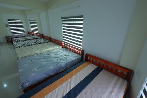 two beds in a room with two windows at Kailasam Residency in Trivandrum