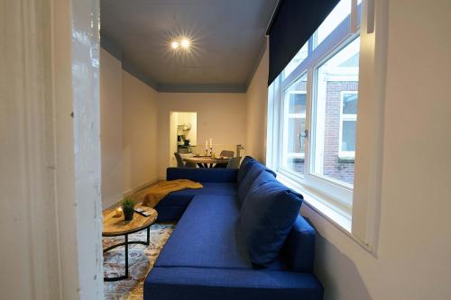 a living room with a blue couch and a window at City Suite Number 4 in Eindhoven