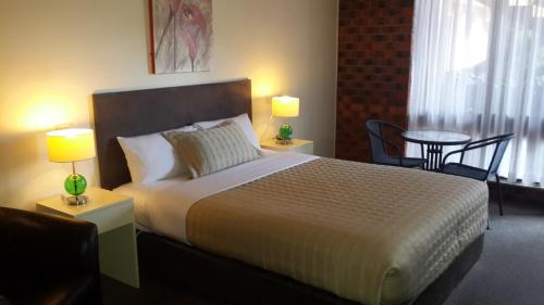 a bedroom with a bed with two lamps and a table at Zero Inn Motel in Nhill