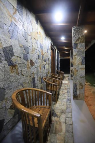 a row of wooden benches against a stone wall at Mango Garden Dambulla in Dambulla