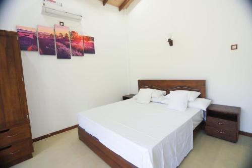 a bedroom with a large white bed with white sheets at Mango Garden Dambulla in Dambulla