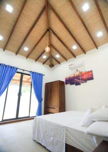 a bedroom with a large bed with blue curtains at Mango Garden Dambulla in Dambulla