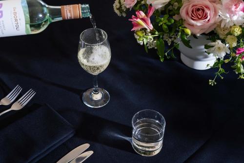 a bottle of wine and a glass on a table with flowers at Mantra Lorne in Lorne