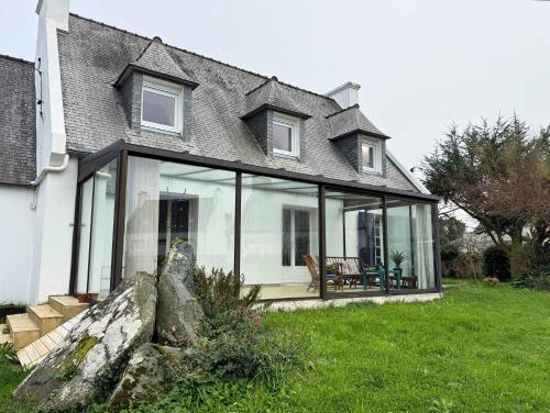 una casa con grandes ventanales en un patio en l'Echappee belle Seaside break for 8 people, en Plougasnou
