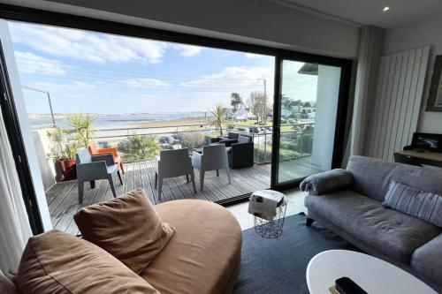 un salon avec un canapé et une grande fenêtre dans l'établissement Luxury T3 neuf de standing Front de mer vue 180, à Larmor-Plage