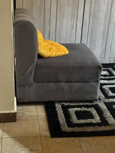 a gray couch with a yellow pillow on top of a rug at Cloud Air in Kampala