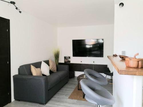 een woonkamer met een zwarte bank en een tafel bij Astérix- CDG Aéroport de Paris - Parc expos Villepinte in Louvres