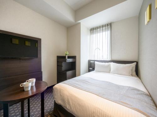 a bedroom with a bed and a table and a television at Akihabara Washington Hotel in Tokyo