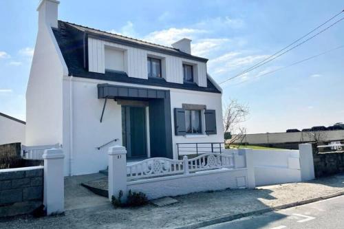 une maison blanche avec une clôture blanche devant elle dans l'établissement Maison de charme vue mer 180 rénovée Accès plage, à Riantec