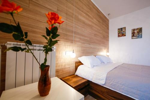 a bedroom with a bed and a vase with a flower on a table at Twin House in Ognyanovo