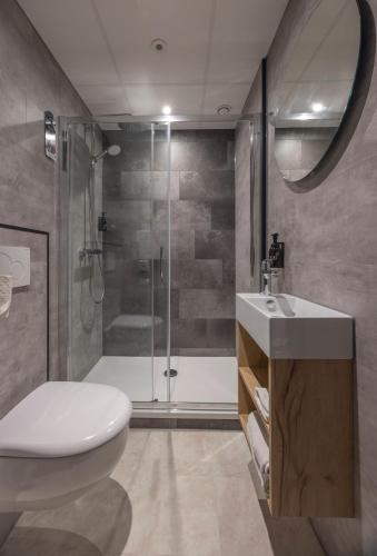 a bathroom with a shower and a toilet and a sink at Fletcher Hotel-Restaurant Mooi Veluwe in Putten