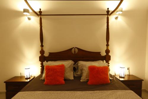 a bed with orange and white pillows on it at Lila Lodge, Villa - Bentota in Bentota
