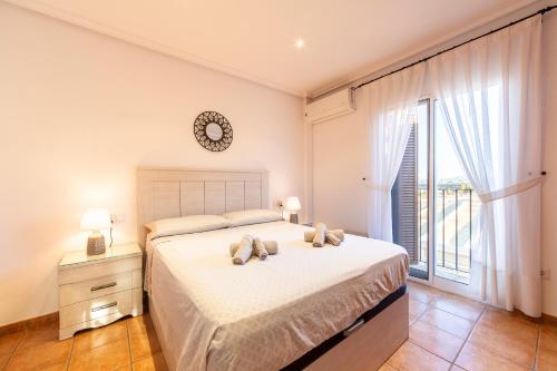 Un dormitorio con una cama con un reloj en la pared. en Al Andalus Residencial Vera Playa 2, en Vera