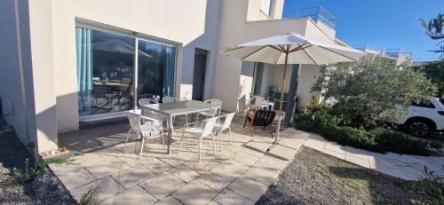 un patio avec une table et un parasol dans l'établissement LA CATALANE, Villa Contemporaine en Bord de Mer et Climatisée, à Sète