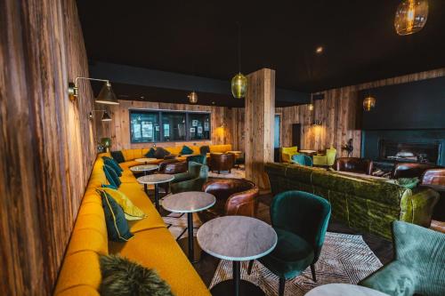 a bar with a yellow couch and tables and chairs at Fahrenheit Seven Val Thorens in Val Thorens