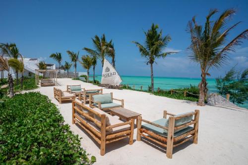 a row of chairs on a beach with the ocean at Kaskazi Hotel Zanzibar in Jambiani