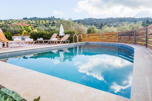 einen Pool mit Stühlen und einem Zaun in der Unterkunft Villa Mazzeto Casa Alonia in Áno Yerakaríon