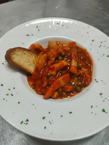 a plate of food with a piece of bread and stew at Hotel Ricci in Rimini