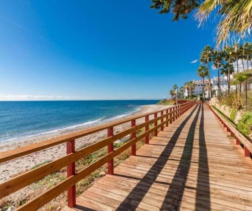 a boardwalk along the beach with palm trees and the ocean at Calypso Holidays in Sitio de Calahonda
