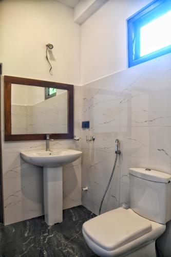 a bathroom with a sink and a toilet and a mirror at The Elite in Udawalawe