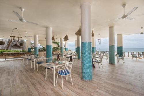 a restaurant with tables and chairs with the ocean in the background at Kiwengwa Beach Resort in Kiwengwa