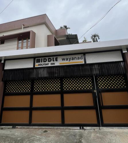 a building with a garage door with a sign on it at MIDDLE WAYANAD HOLYDAY Inn in Kaniyāmbetta