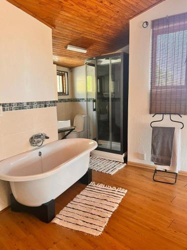 ein Badezimmer mit Badewanne und Glasdusche in der Unterkunft Guesthouse Oaktree fourways in Fourways
