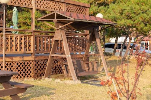 a wooden play structure with a roof on top at Ganghwa Granblue Pension in Incheon