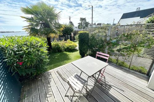 une terrasse en bois avec une table et une chaise. dans l'établissement Appartement T2 super cosy - Front de mer, à Larmor-Plage