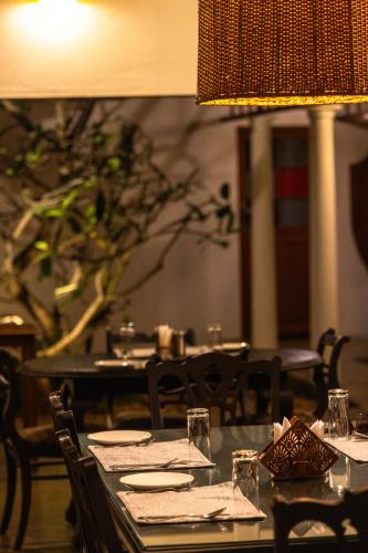 a dining room with a table with plates and glasses at Cranganor History Café & Riverside Château in Parūr