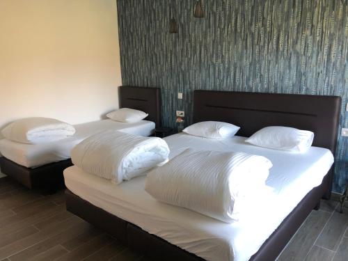 two beds in a room with white sheets and pillows at Gîte Ôfé in Ouffet