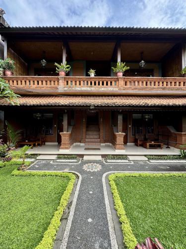 a building with a walkway in front of a yard at Danasari Homestay in Ubud