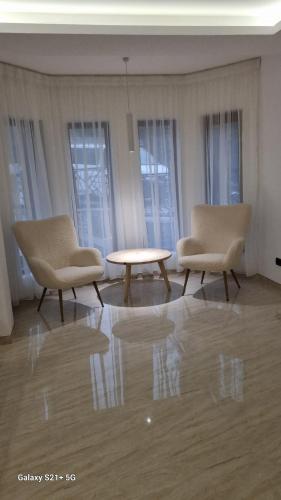 two chairs and a table in a room with windows at Casa Anda in Pucioasa
