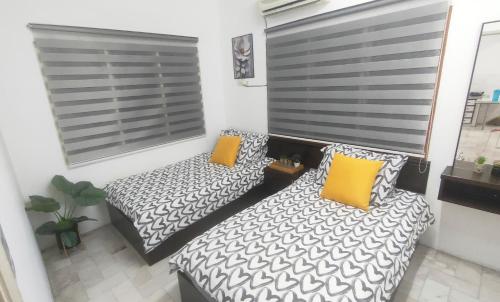 two beds in a small room with yellow pillows at 33 HOMESTAY 4 Room 5 MINUTE TO LEANING TOWER in Teluk Intan
