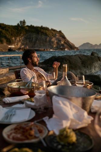 a man sitting at a table with plates of food at Maya Beach Resort in Massa Lubrense