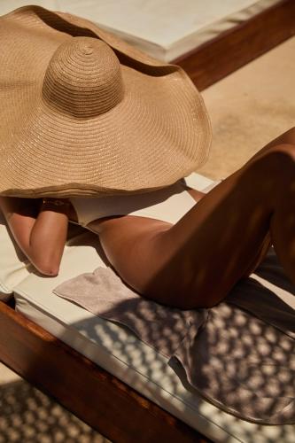 a woman wearing a hat sitting on a table at Maya Beach Resort in Massa Lubrense