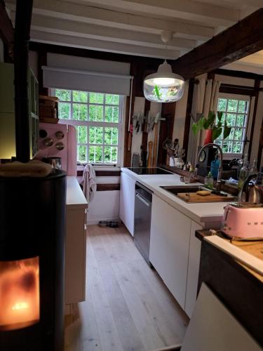 La cuisine est équipée de comptoirs blancs et de plaques de cuisson. dans l'établissement Maison au bord de la Seine, à Vatteville