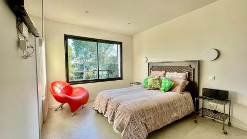 une chambre avec un lit et une chaise rouge dans l'établissement Maison La pause Contemporaine et Piscine Privée, à Lambesc