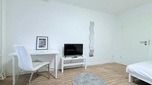a white room with a desk and a television at Neumünster Apartments direkt an der Stadthalle mit WLAN & Parkplatz in Neumünster