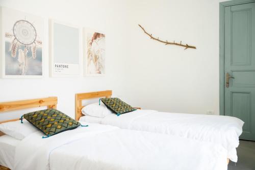 two beds in a room with white walls at חאן טשרניחובסקי in ‘Ofer